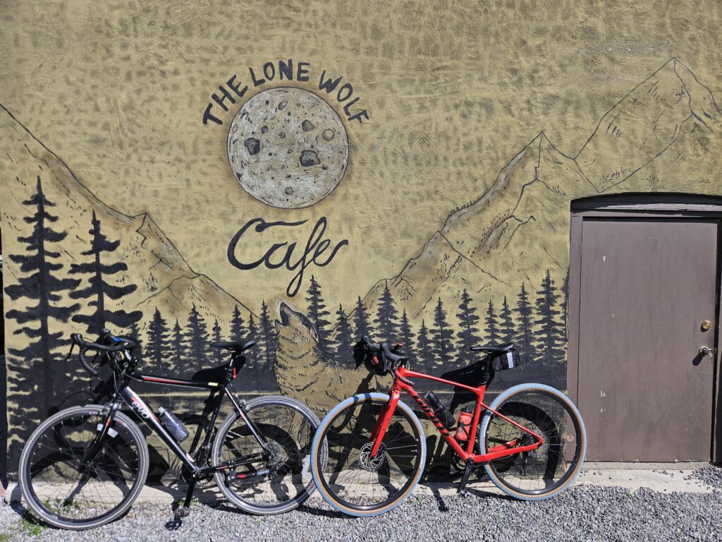 Two bikes against a wall mural of The Lone Wolf Cafe.